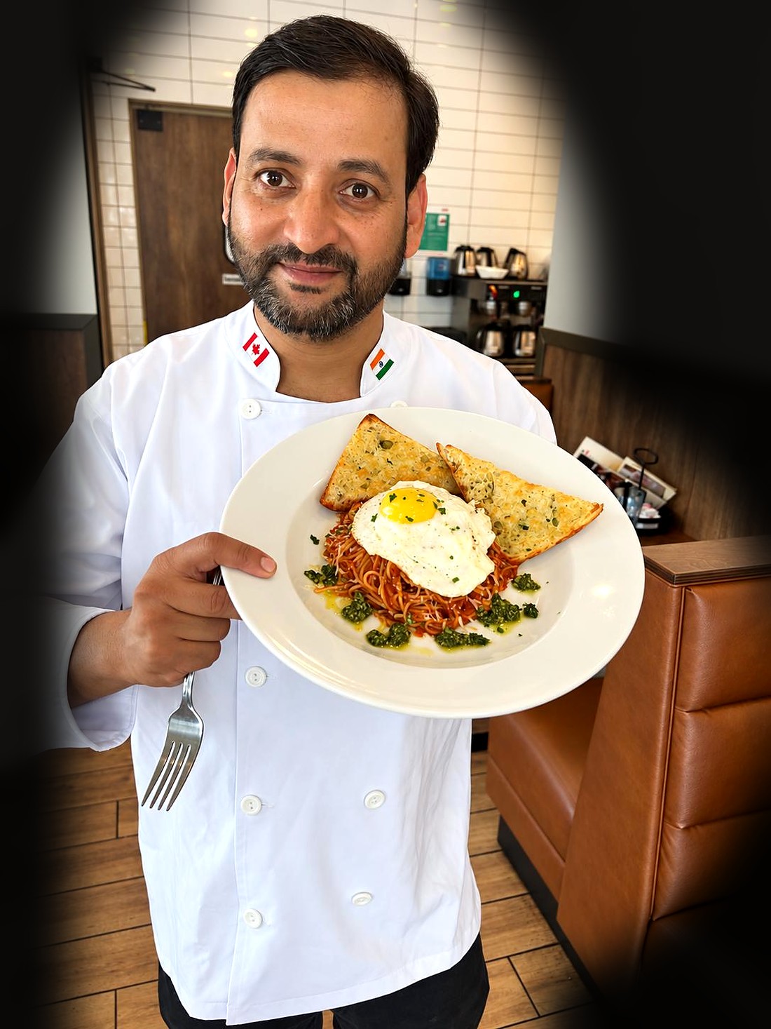 Chef Rajpal Singh Ranghar holding a plate of spaghetti with a fried egg and garlic bread
